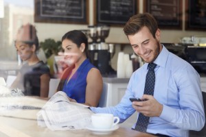 Man smiling and looking at smartphone in a coffee shop
